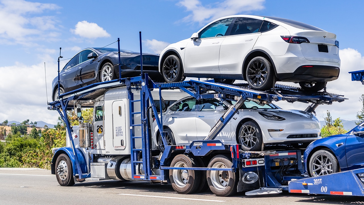 Car being loaded onto a shipping trailer with a driver overseeing the process, illustrating the car shipping process.